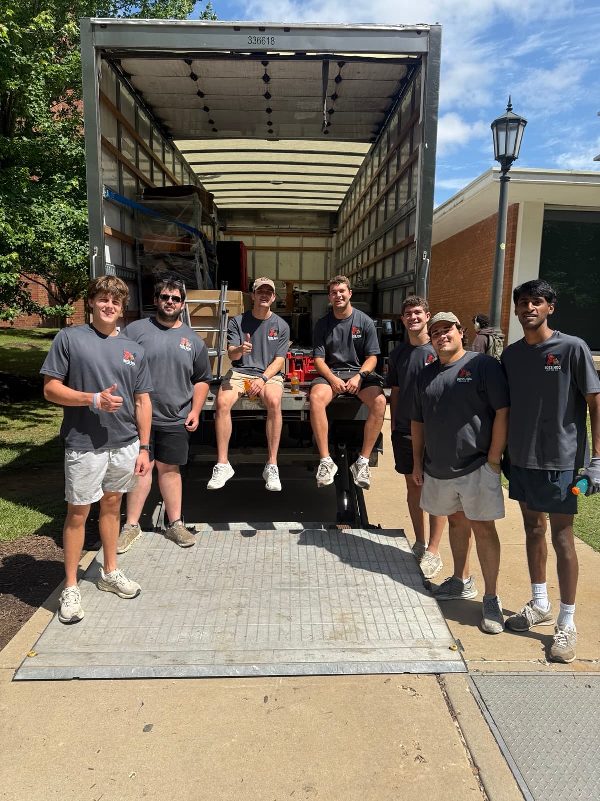 Seven Boss Hog movers gathered around the ramp of a loaded moving truck