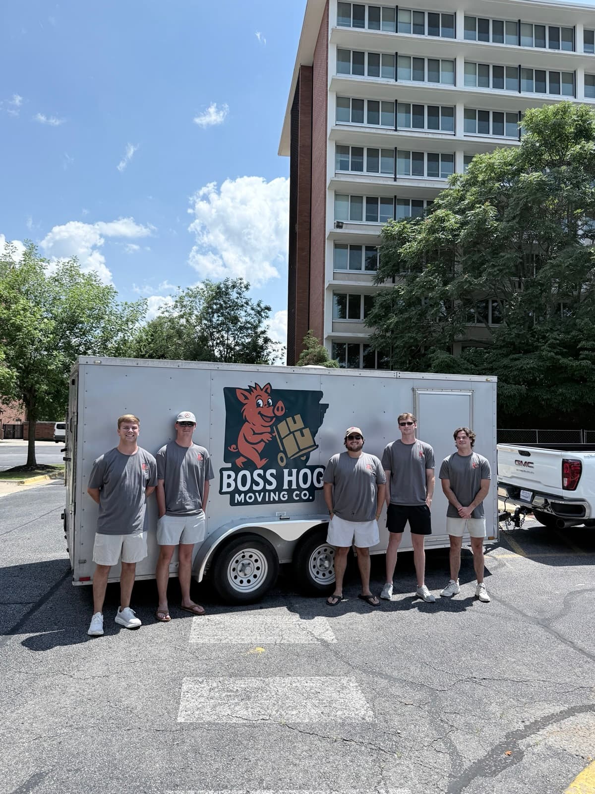 Boss Hog crew standing beside the branded moving trailer outside a residence hall